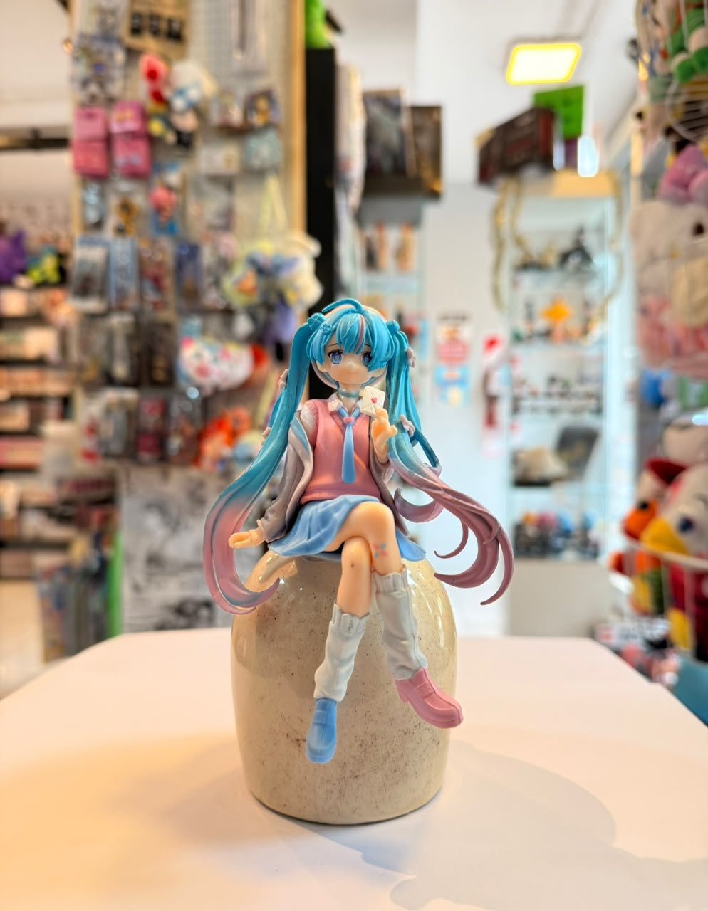 FIGURA DE MIKU SENTADA SOSTENIENDO PEQUEÑA CARTA