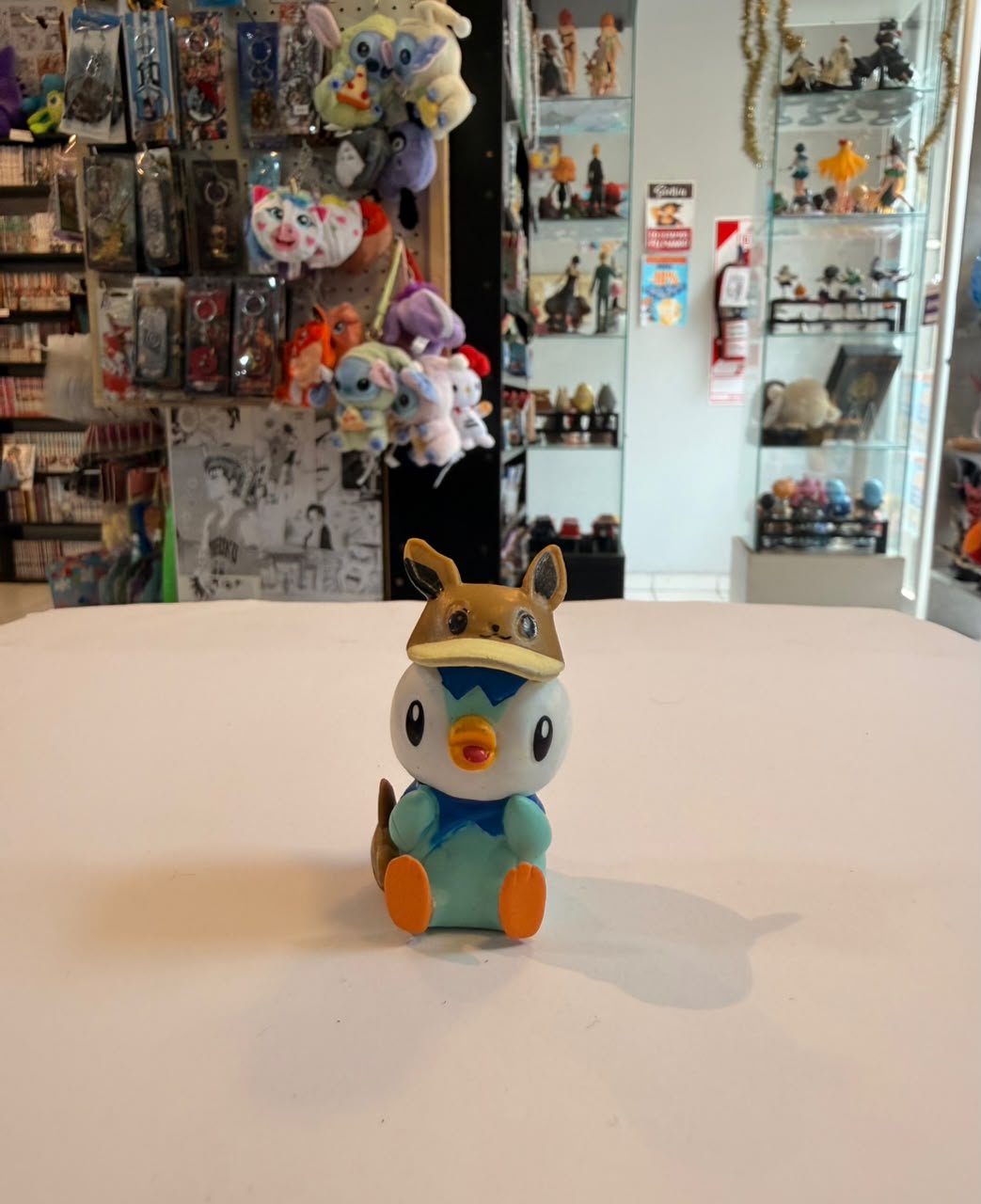 FIGURA GASHAPON DE PIPLUP CON GORRO DE EEVEE